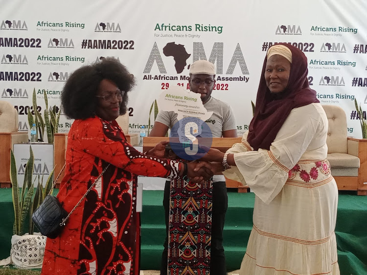 Africans Rising resource mobilization lead Dorothy Adebanjo receives a branded African piece from Former Gambia Vice President Fatoumata Tambajang during the All African Movement Assembly in Arusha on August 31,2022