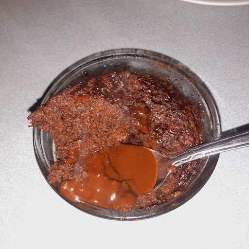 Pudding cake after baked with a spoonful scooped out to show pudding/sauce on bottom. 