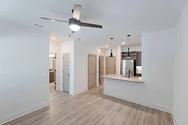 Open concept living spaces with wood finish flooring, ceiling fan with lighting, and white walls