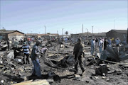 PICKING UP THE PIECES: Hundreds of Langa residents were left homeless after more than 350 shacks and 13 hostels burnt to the ground at midnight on Monday. A woman in her 60s, believed to be from  Eastern Cape,  died in the inferno. Photo: Unathi Obose