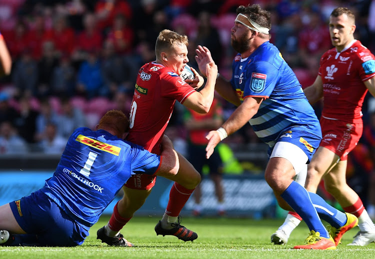 Steven Kitshoff (left) tackles Sam Costelow of the Scarlets before Stormers' teammate Frans Malherbe lends a hand in a URC clash. Kitshoff will equal Malherbe's record 124 appearances in Saturday's Champions Cup match against Clermont.