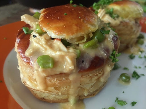 Two puff pastries on a plate with a chicken sauce.