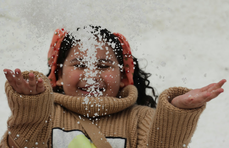 A girl throws up some salt crystals as she visits the small salt hills in the canal city of Port Fouad, Egypt March 12, 2021.