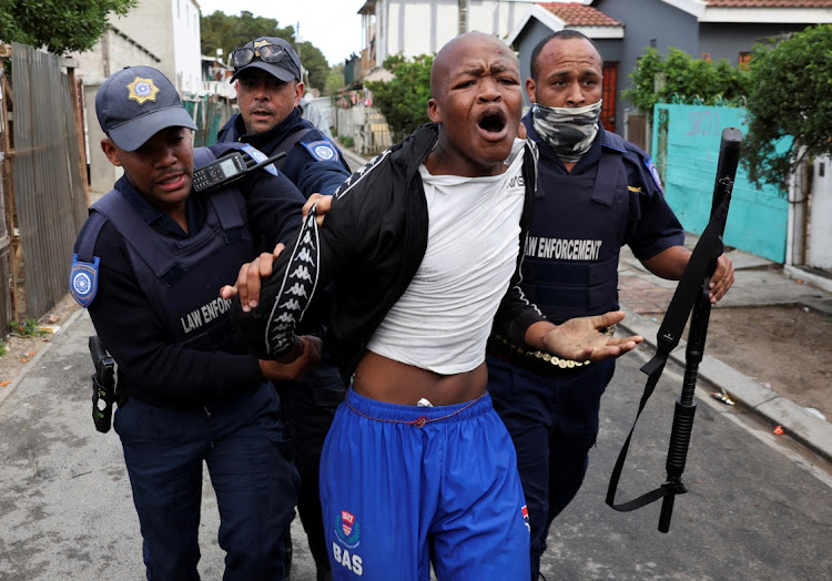 Law enforcement officers detain a protestor in Masiphumelele during the strike by taxi operators on August 8, 2023.