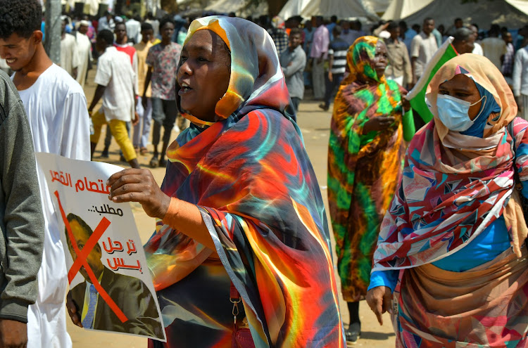 A Sudanese demonstrator holds a poster bearing a crossed out face of Prime Minister Abdalla Hamdok, during a rally in front the presidential palace in the capital Khartoum, demanding a return to military rule, on October 21, 2021.