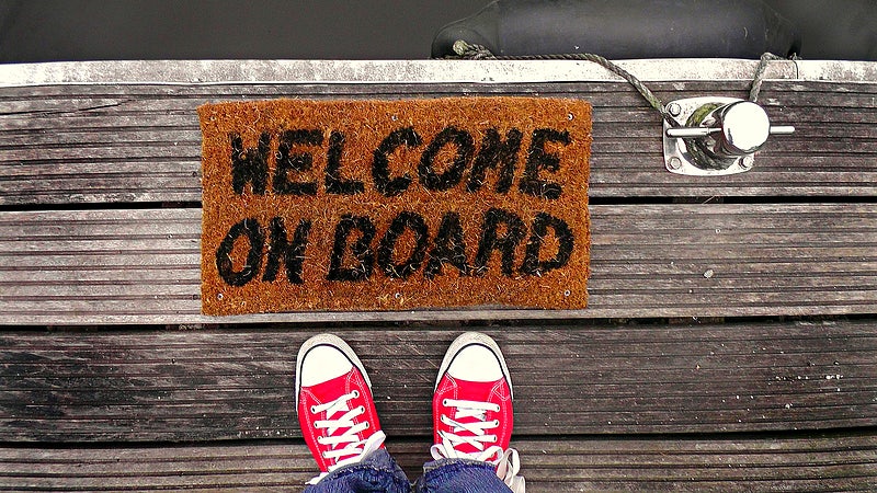 Image of red sneakers in front of welcome on board entry mat