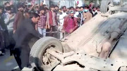 A mob hits an overturned car with sticks after an attack on a factory in Sialkot, Pakistan December 3, 2021, in this screen grab taken from a video.   