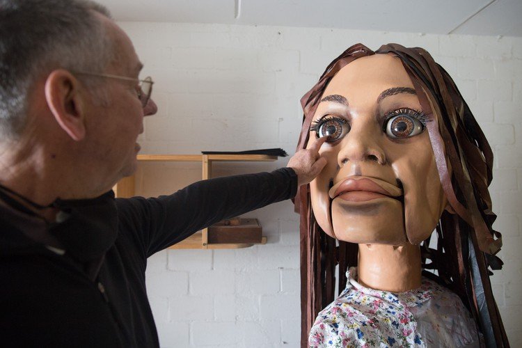 Designer Adrian Kohler with the giant “Little Amal” puppet. The eyes are electronically controlled by a joystick. All the other movements, of the mouth, head and arms, are mechanical.