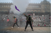 A woman waves a flag during a protest outside the National Palace on International Women's Day in Mexico City on March 8 2021. 
