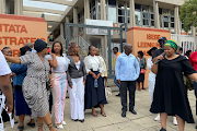 Doctor Yolisa Siphambo-Mngxali, fourth from left (wearing a white blouse and navy skirt) and her family outside the Mthatha magistrate’s court, flanked by supporters.