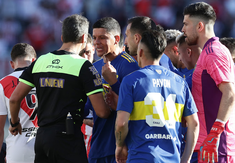 Boca Juniors' defender Marcos Rojo (C) argues Argentinian referee Fernando Rapallini (L) during the Argentine Professional Football League match against River Plate at the Monumental stadium in Buenos Aires