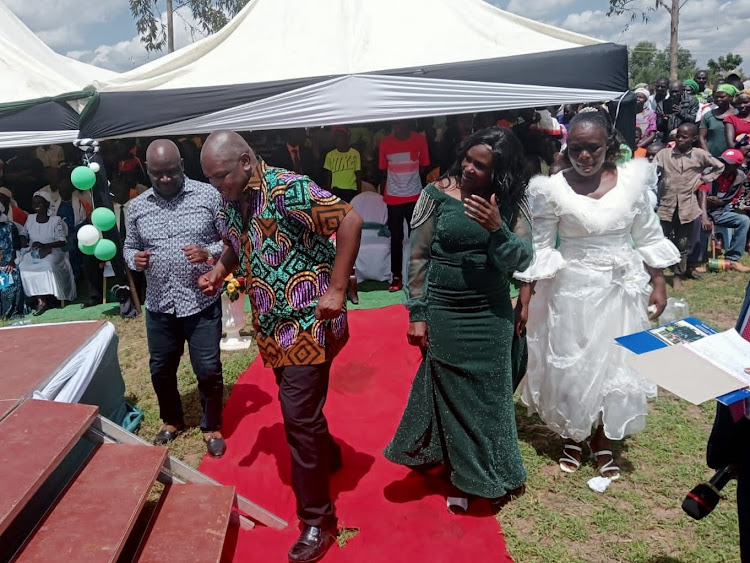 Kabuchai MP Majimbo Kalasinga enjoys a dance with Kiminini MP Kakai Bisau on Friday during the homecoming celebration.