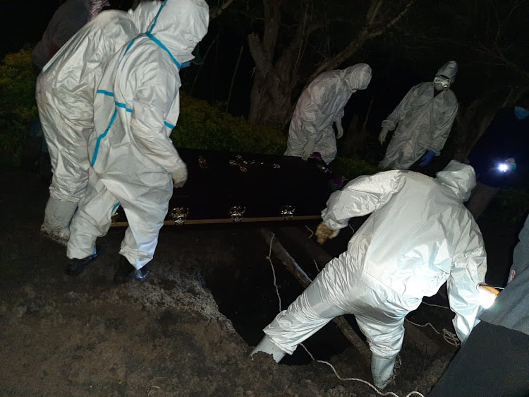 Health workers prepare to bury the body of A Covid-19 victim at Kagawet in Bomet on Wednesday night