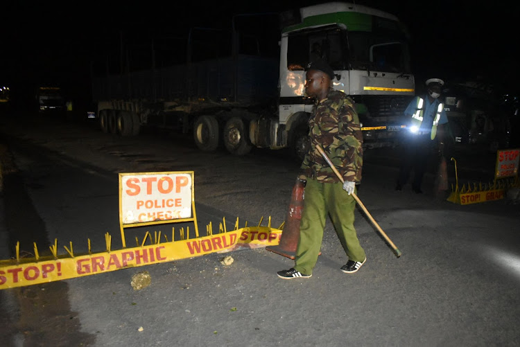 Police keep vigil at a barrier in Mtwapa on the Mombasa-Malindi highway at the start of a curfew on March 27