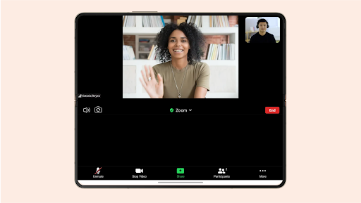 Um telemóvel dobrável que apresenta uma chamada no Zoom com 2 pessoas a sorrir e a falar uma com a outra.
