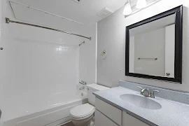 Bathroom with neutral walls, a light vanity with stone-inspired counter & shower/tub with tile-inspired walls & curtain rod.