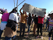 Protesters outside the Cremona Cheese Factory demand to be allowed to settle on vacant land owned by the factory.