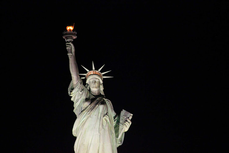 The Statue of Liberty between New York and New Jersey at night.