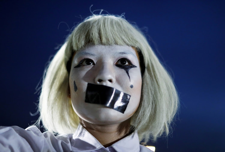 A pro-democracy student wearing make-up and a tape covering her mouth attends a rally at Mahidol University outside Bangkok, Thailand, to demand government reforms.