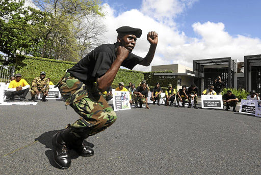 A member of the MK Inkululeko Foundation demonstrates his fighting skills while his comrades watch. / ESA ALEXANDER