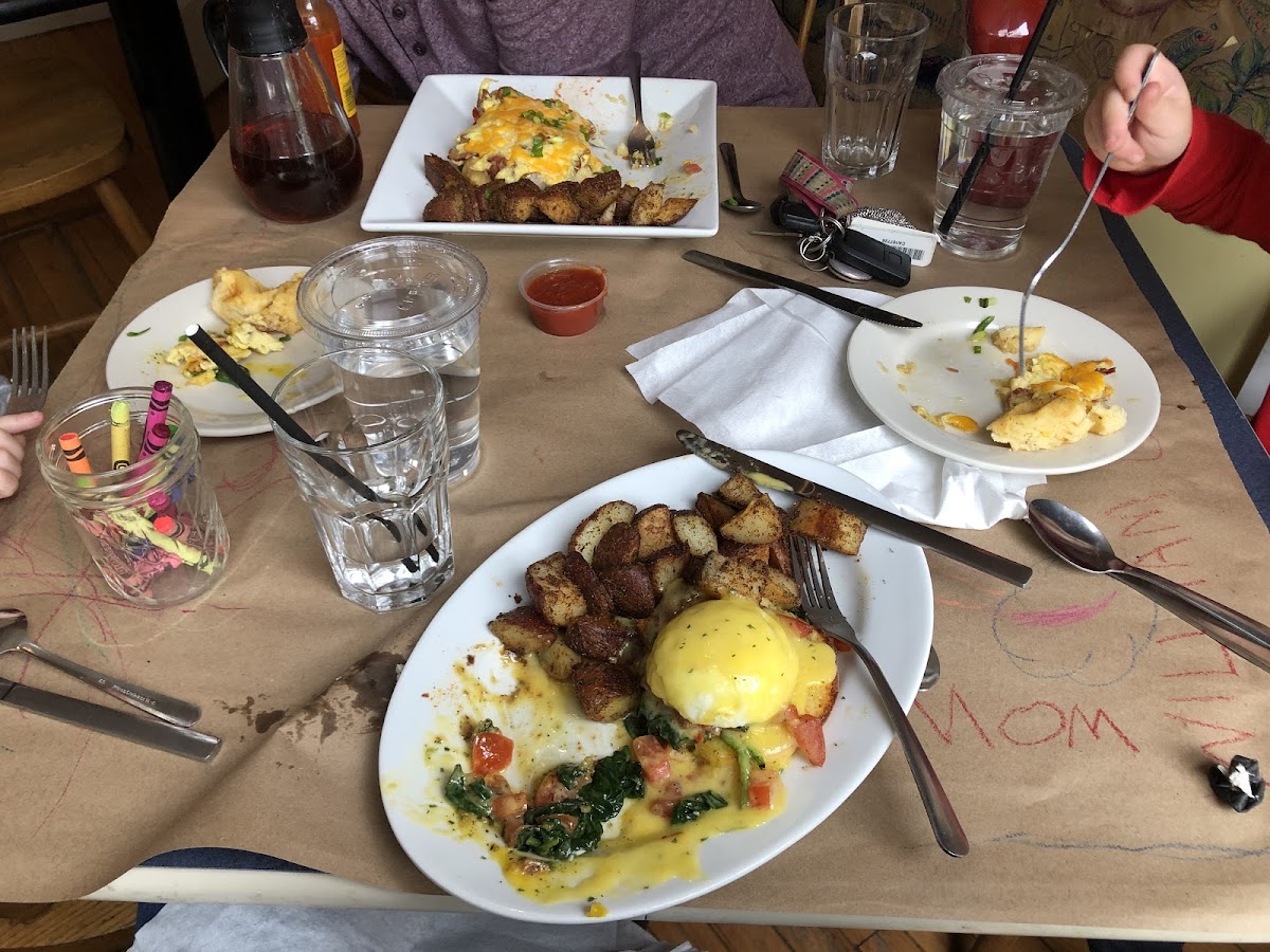 Eggs Benedict with spinach and tomato. On the other side of the table the waffle pizza.