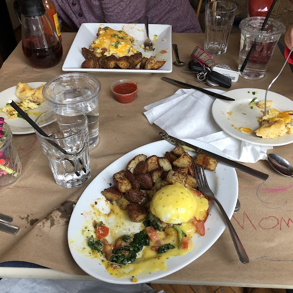 Eggs Benedict with spinach and tomato. On the other side of the table the waffle pizza.