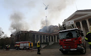 A helicopter water-bombs the fire near the Jagger Reading Room at the University of Cape Town.