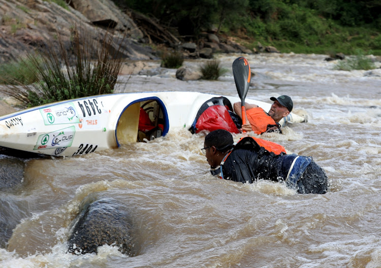 Canoeists capsize as they paddle down rapids on the first day of the Dusi.