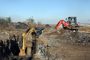 Joburg water officials excavate a manhole in Dlamini to allow divers to access a pipe.
