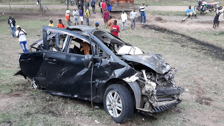 Members of the public view the wreck of a personal car that was hit by two trailers in Marula Naivasha along the Nairobi-Nakuru Highway killing six members of a family