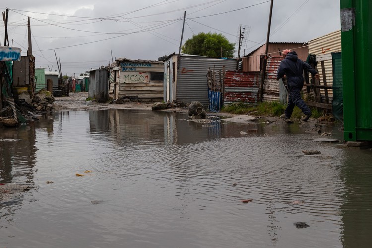 A resident walks along a flooded road in Marikana, Philippi.