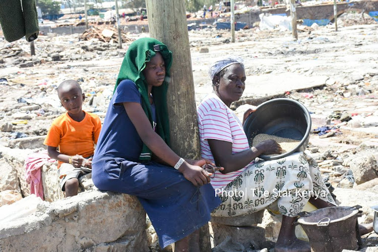 Benta Serena and Isaac Ishimuli seat next to their grand mother Dorcus Anyona as she prepares something to eat in Mukuru Kwa Njenga Slums on 22, November 2021./ MERCY MUMO