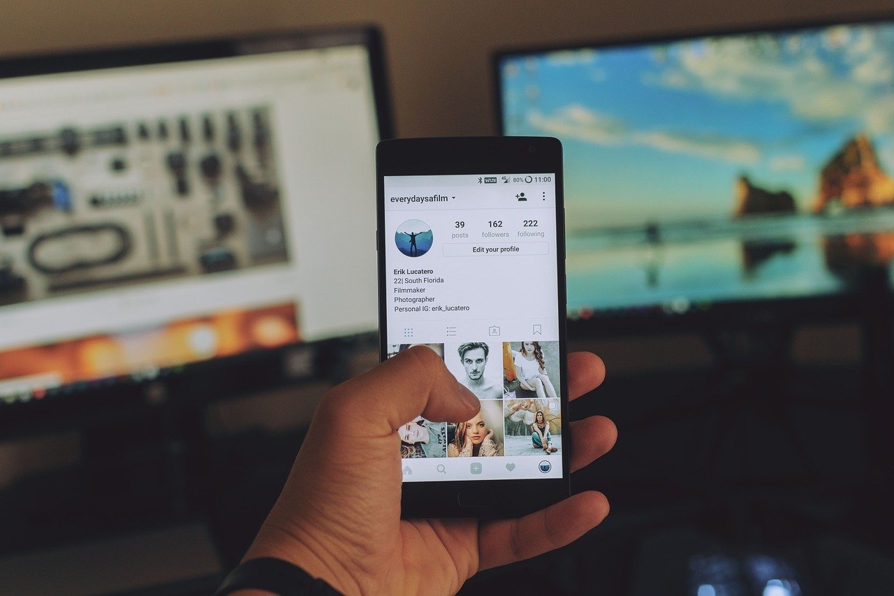 a man holding a phone looking at an Instagram page