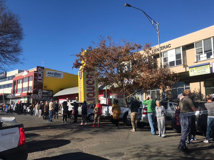 A group of people queuing outside the Beyers Naude Liquor City ahead of its 9am opening on Monday.