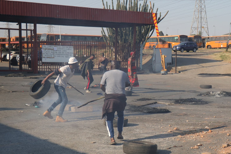 Striking Putco employees blocking the entrance to the bus depot in New Canada, Soweto, with burning tyres and rocks.