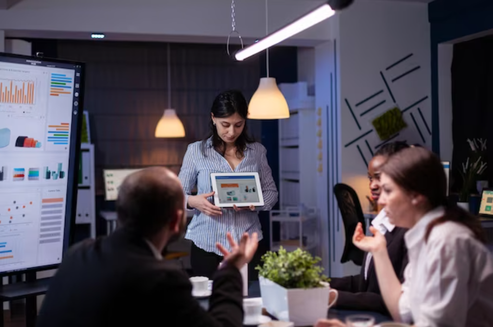 woman shows a tablet with photos for the people on meeting