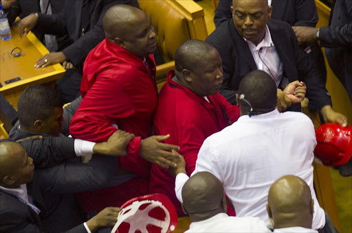ALTERNATIVE CROP Leader of the Economic Freedom Fighters, Julius Malema (C), and members of his party, wearing red uniforms, clash with security forces during South African President's State of the Nation address in Cape Town on February 12, 2015. Security forces were called to eject radical lawmakers who interrupted South African President Jacob Zuma's annual state of the nation address to parliament. The members of the Economic Freedom fighters led by populist firebrand Julius Malema had caused uproar as they demanded that Zuma repay millions of taxpayers money spent on his private residence. AFP PHOTO/ POOL / RODGER BOSCH