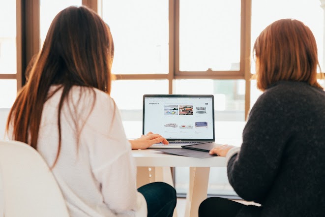 Two women looking at a computer together.