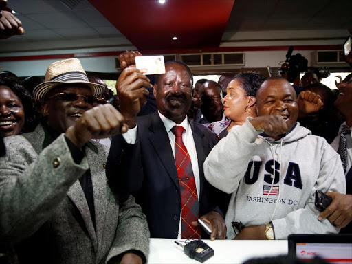 NASA leader Raila Odinga (C) holds a new sim card at an Airtel telecommunications shop as part of his party's campaign to boycott three big companies, including telecoms giant Safaricom, in Nairobi, Kenya November 6, 2017. /REUTERS