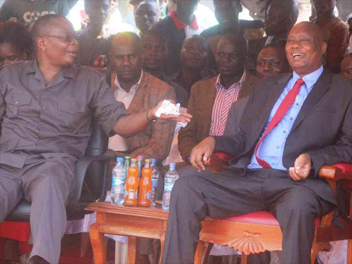 Funyula MP Paul Otuoma share light moments with Busia Governor Sospeter Ojaamong during Mashujaa Day celebrations at Funyula Stadium on Friday/ JANE CHEROTICH.