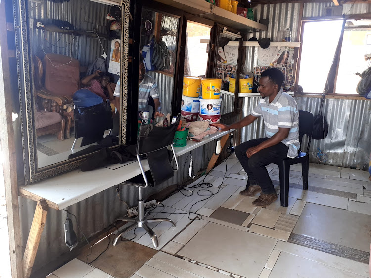 Thulani Khoza sits in his empty salon while he waits for customers after load-shedding.