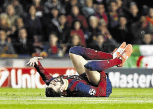 OUCH!: Barcelona defender Gerard Pique in agony on the Nou Camp pitch during Tuesday's Champions League match against Atletico Madrid. PHOTO: QUIQUE GARCIA/AFP