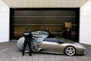 Police officers uncover a 2007 Lamborghini Murcielago, part of the fleet of vehicles seized by the government from politicians and organised crime.