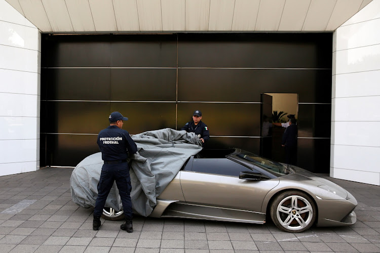 Police officers uncover a 2007 Lamborghini Murcielago, part of the fleet of vehicles seized by the government from politicians and organised crime.