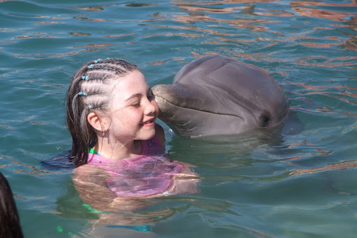 A dolphin gives a girl a kiss at a marine attraction on Grand Bahama Island. 