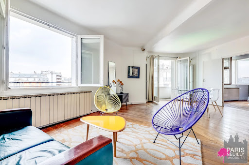 Modern living room with colorful chairs and view in this luxury property for sale in Paris 17ème ($943,626 - 86 m²)