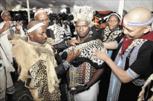 WELCOME TO THE CLUB: Xhosa King Mpendulo Sigcawu, left, ties Chief Velile Ndevu's leaders shoulder wear to mark his annointment as the head of Imiganu Traditional Council during a ceremony held at Mkhathazo Great Place near Elliotdale, Eastern Cape. Helping the king are chiefs Ngangomhlaba Matanzima and Phathekile Holomisa. The writer says traditional leaders deserve the recognition they are getting. Photo: Lulamile Feni