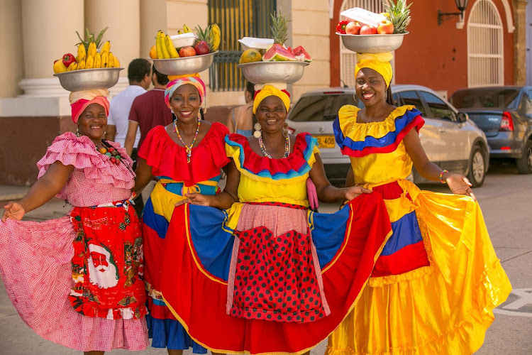 Women pose in traditional dress in Old Cartagena, Colombia. 