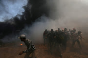 Palestinian demonstrators run for cover during a protest against US embassy move to Jerusalem and ahead of the 70th anniversary of Nakba, at the Israel-Gaza border in the southern Gaza Strip May 14, 2018.