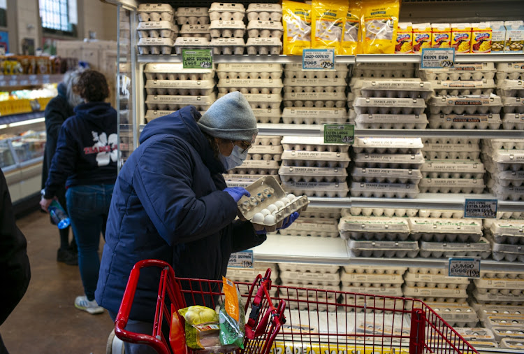 A shopper wearing a surgical mask and latex gloves inspects a dozen eggs at a Trader Joes on April 3, 2020 in the Brooklyn borough of New York City.